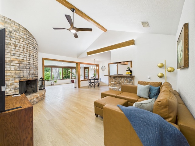 living area featuring beam ceiling, a fireplace, light wood-style flooring, a ceiling fan, and visible vents
