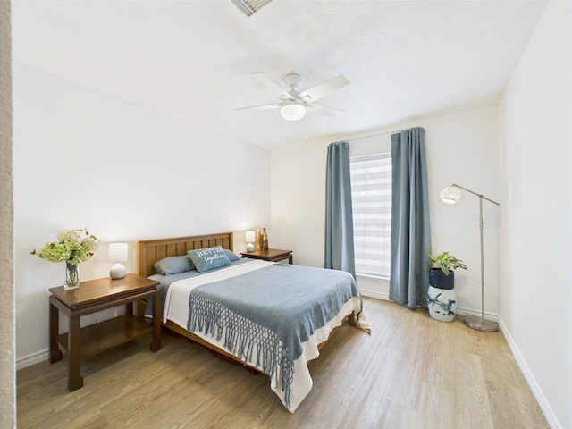 bedroom with baseboards, a ceiling fan, and light wood-type flooring