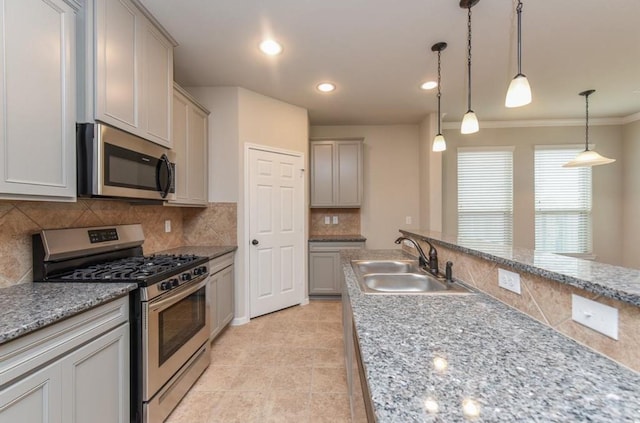 kitchen featuring crown molding, a sink, backsplash, decorative light fixtures, and stainless steel appliances