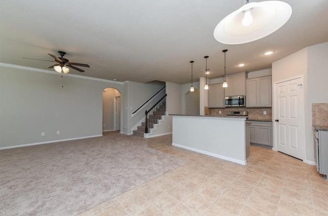 kitchen with ceiling fan, hanging light fixtures, arched walkways, stainless steel microwave, and gray cabinetry
