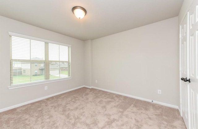 spare room featuring baseboards and light carpet