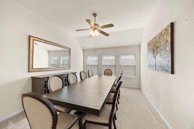 dining area featuring a ceiling fan, baseboards, light colored carpet, and lofted ceiling