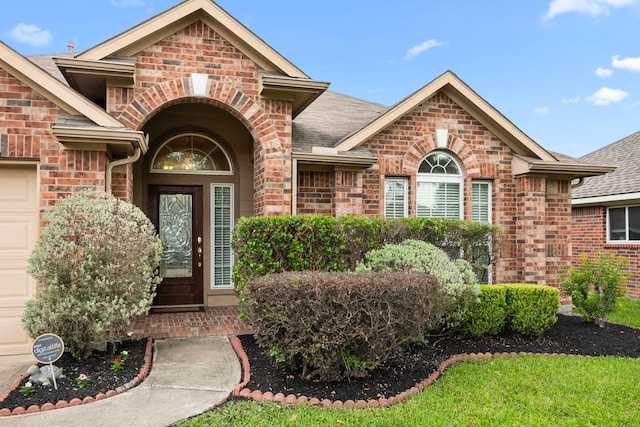 entrance to property with brick siding and a shingled roof