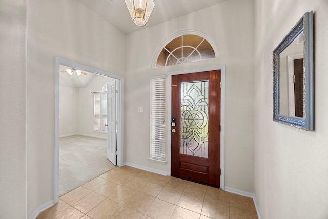 carpeted foyer featuring high vaulted ceiling, ceiling fan, baseboards, and tile patterned floors