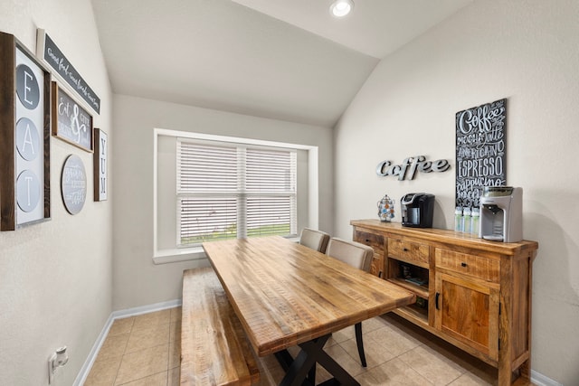 dining room featuring baseboards, vaulted ceiling, and light tile patterned floors