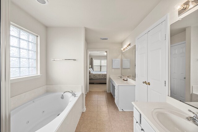 ensuite bathroom featuring tile patterned floors, vanity, ensuite bath, and a wealth of natural light