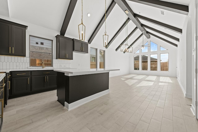 kitchen featuring hanging light fixtures, beam ceiling, light countertops, backsplash, and a kitchen island
