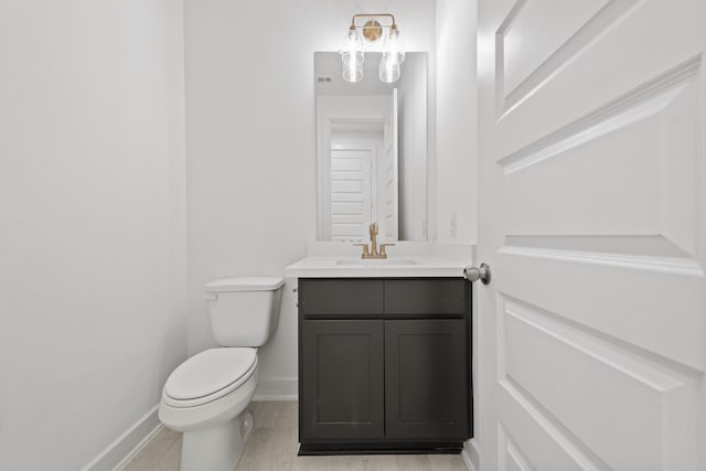 half bath with vanity, baseboards, and toilet