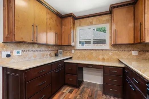 kitchen featuring built in study area, light countertops, decorative backsplash, dark wood-type flooring, and ornamental molding