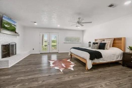 bedroom with visible vents, access to exterior, wood finished floors, and a fireplace