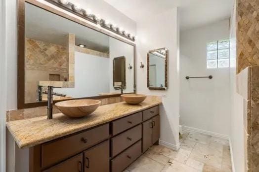 bathroom with double vanity, a sink, marble finish floor, and baseboards
