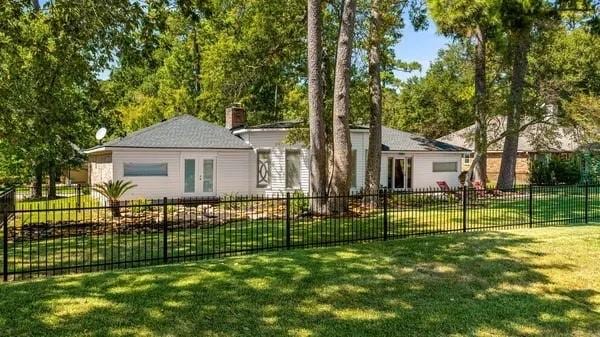 view of front facade featuring fence private yard, a front lawn, french doors, and a chimney