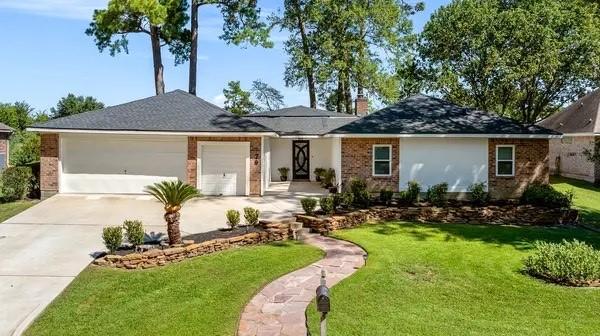 ranch-style house featuring brick siding, an attached garage, driveway, and a front lawn