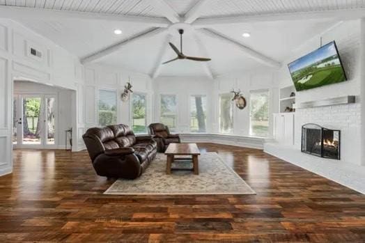 living room with a ceiling fan, vaulted ceiling with beams, wood finished floors, and a fireplace