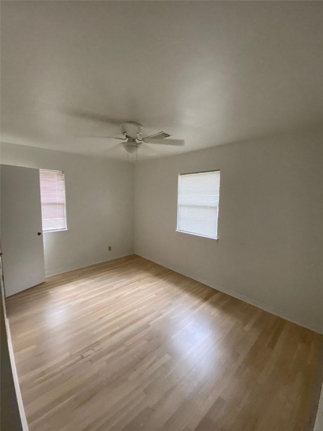 empty room featuring a healthy amount of sunlight, ceiling fan, and light wood-style flooring