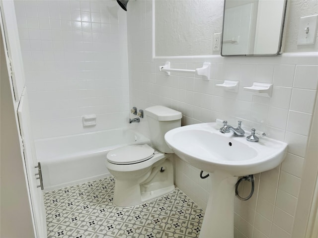 full bath with toilet, tile walls, tub / shower combination, and a wainscoted wall