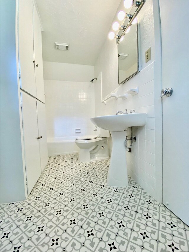 bathroom featuring visible vents, toilet, and tile walls