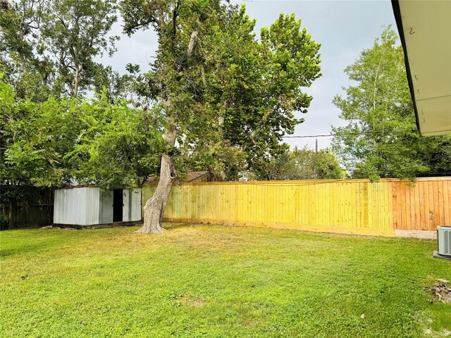 view of yard with a storage unit, a fenced backyard, and an outbuilding