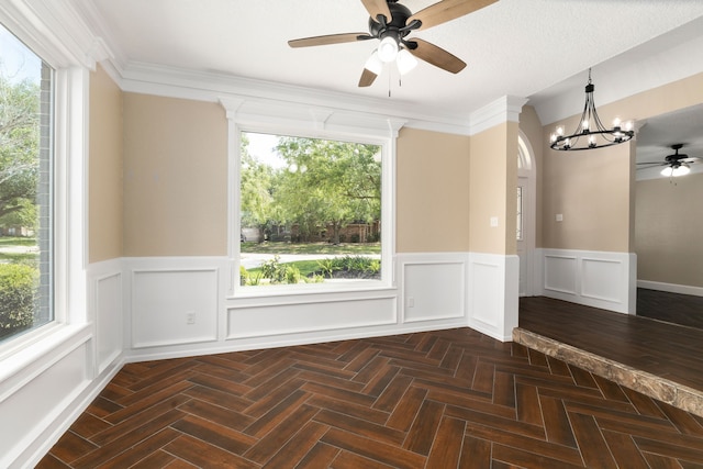 spare room with a wainscoted wall, ceiling fan with notable chandelier, arched walkways, and a decorative wall