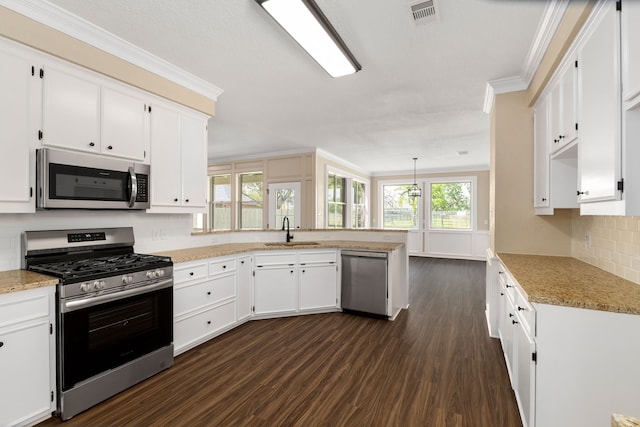 kitchen featuring crown molding, visible vents, a peninsula, a sink, and stainless steel appliances