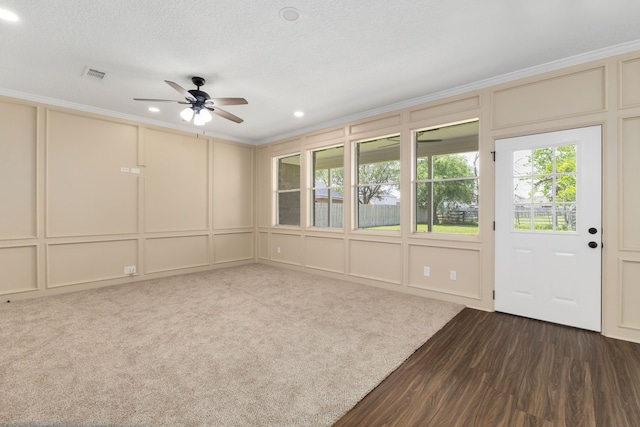 unfurnished room featuring crown molding, a ceiling fan, a decorative wall, and visible vents