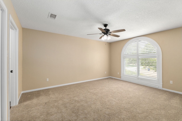 empty room with baseboards, a ceiling fan, carpet, and a textured ceiling