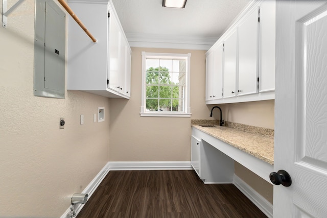 laundry area with dark wood-style flooring, baseboards, electric panel, a sink, and cabinet space