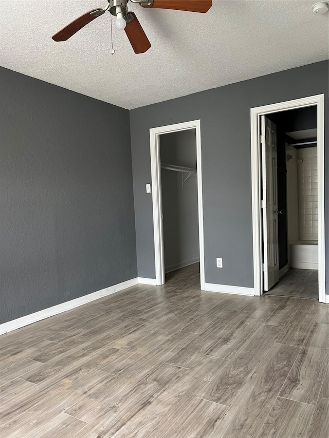 8100 Creekbend Dr Unit 178, Houston, TX 77071 - unfurnished bedroom with wood finished floors, a textured ceiling, a closet, a spacious closet, and baseboards