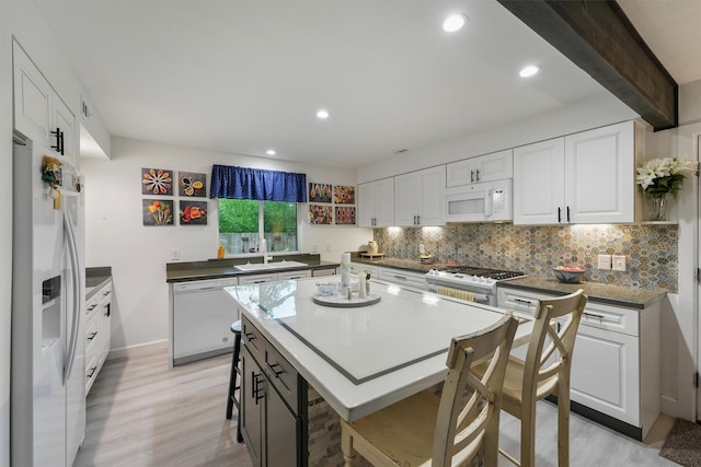 kitchen with a sink, white appliances, and white cabinetry