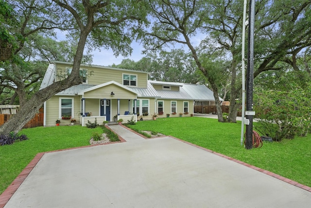 view of front of house with covered porch, fence, metal roof, and a front lawn