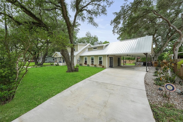 view of front of house with fence, a front lawn, an attached carport, driveway, and metal roof
