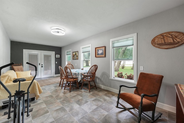 dining space featuring baseboards, stone finish floor, and french doors