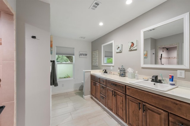 bathroom with a sink, baseboards, double vanity, and visible vents