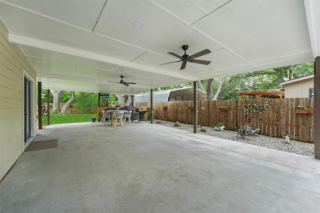 view of patio with fence, outdoor dining space, ceiling fan, and a carport