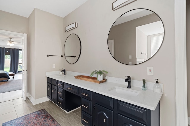ensuite bathroom with double vanity, ceiling fan, and baseboards