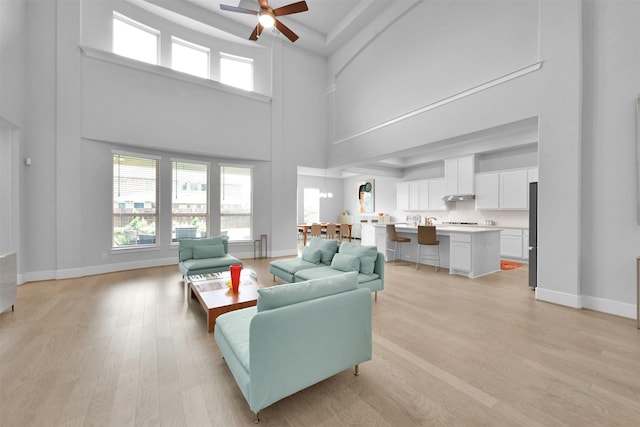 27954 Presley Park Dr, Spring, TX 77386 - living room with baseboards, ceiling fan, light wood finished floors, and a towering ceiling