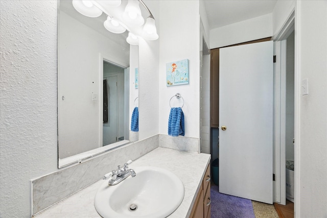 bathroom featuring a textured wall and vanity
