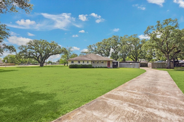 view of front facade featuring fence, driveway, and a front yard