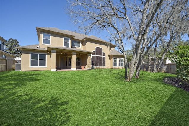 back of house with a lawn, a fenced backyard, and stucco siding