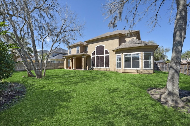 back of property featuring a lawn, a fenced backyard, and stucco siding
