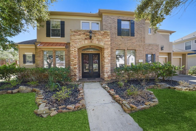 view of front of house with french doors, stucco siding, brick siding, and a front yard