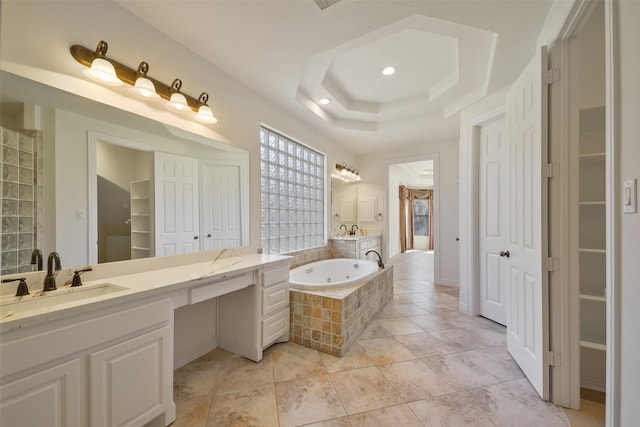 full bath with vanity, a closet, a raised ceiling, and a jetted tub