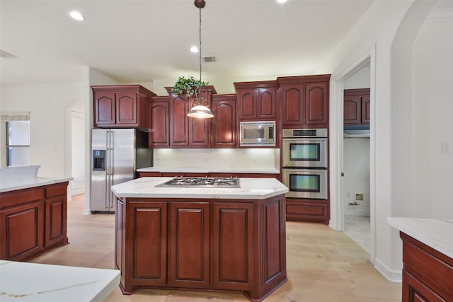 kitchen with visible vents, pendant lighting, arched walkways, dark brown cabinets, and stainless steel appliances