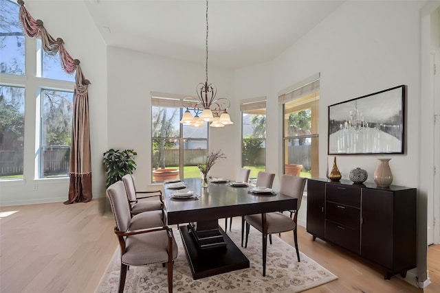 dining space featuring baseboards, light wood finished floors, and a chandelier