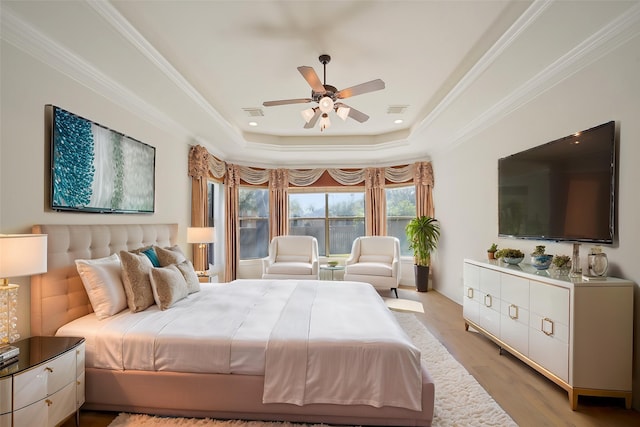 bedroom featuring ceiling fan, visible vents, crown molding, wood finished floors, and a raised ceiling