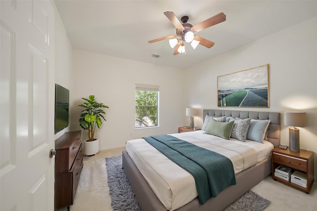 bedroom with visible vents, a ceiling fan, and light colored carpet