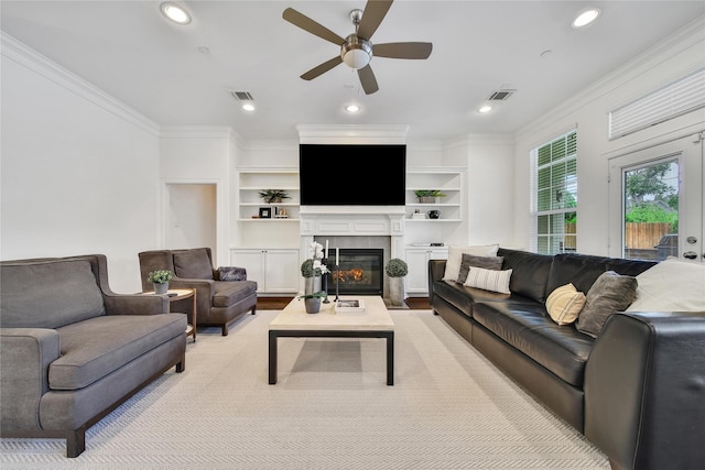 8322 Merlin Dr, Spring Valley Village, TX 77055 - living room featuring a ceiling fan, crown molding, a tiled fireplace, recessed lighting, and built in features