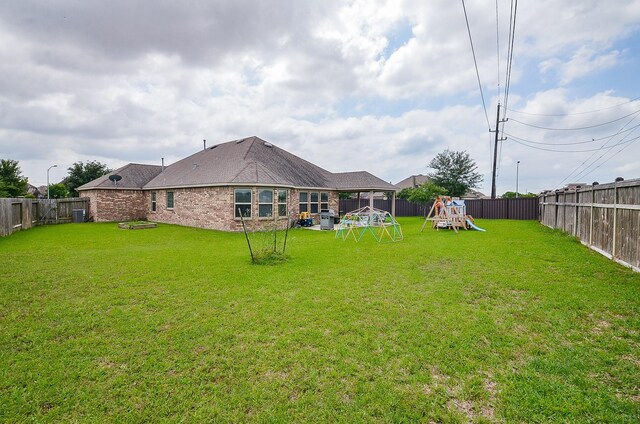 view of yard featuring cooling unit, a fenced backyard, and a playground