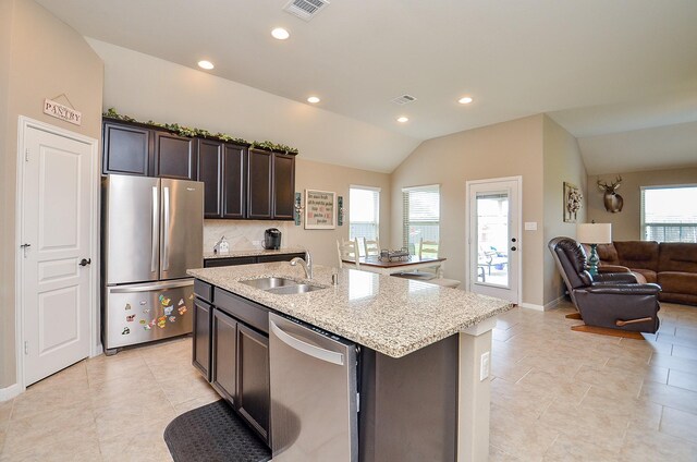 kitchen with visible vents, a sink, light stone counters, open floor plan, and stainless steel appliances