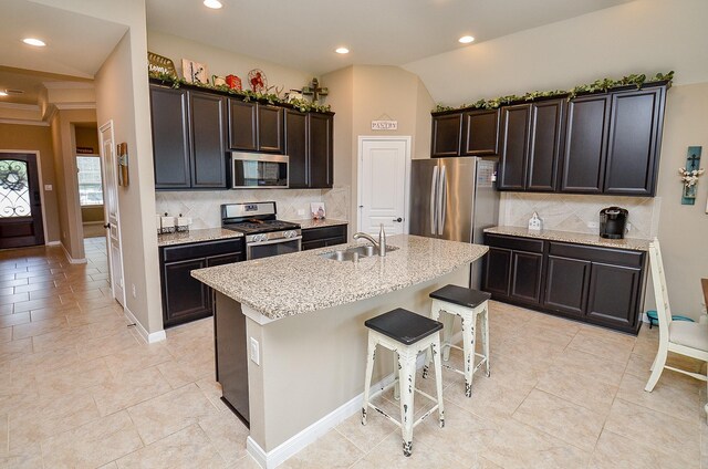 kitchen with a sink, appliances with stainless steel finishes, tasteful backsplash, and light stone countertops